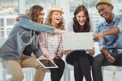 Business people laughing while pointing at laptop