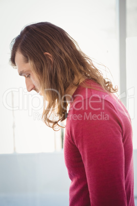 Side view of man looking down while standing in office