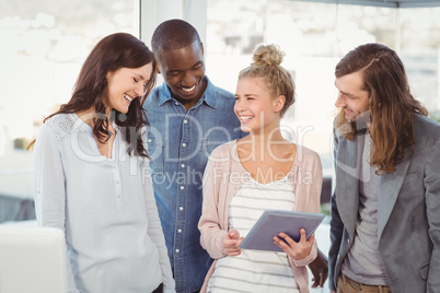 Smiling woman holding digital tablet and discussing with coworke Smiling woman holding digital tablet and discussing with coworke