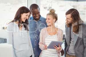 Smiling woman holding digital tablet and discussing with coworke