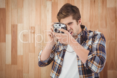 Hipster photographing against wooden wall