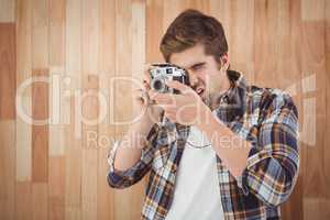 Hipster photographing against wooden wall