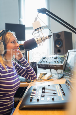 Happy female radio host broadcasting through microphone