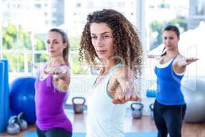 Focused women doing warrior II pose