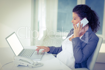 Pregnant businesswoman talking on mobile phone while working