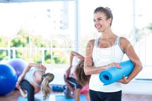 Happy woman holding exercising mat