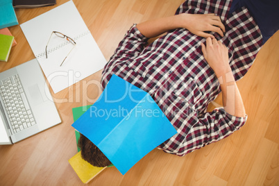 Creative businessman lying on hardwood floor