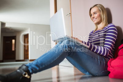 Female student sitting on flooring using laptop