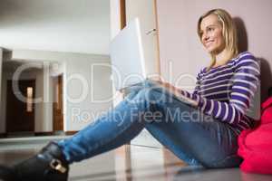 Female student sitting on flooring using laptop