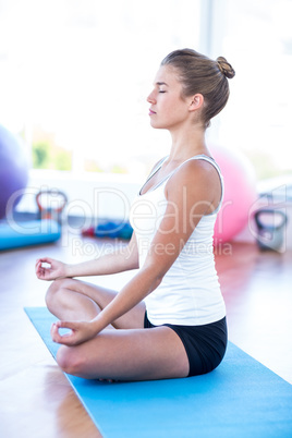 Side view of woman doing meditation on yoga mat