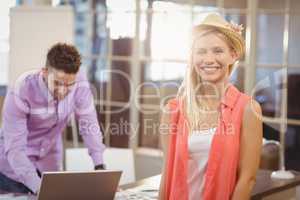 Business woman wearing hat standing by male colleague