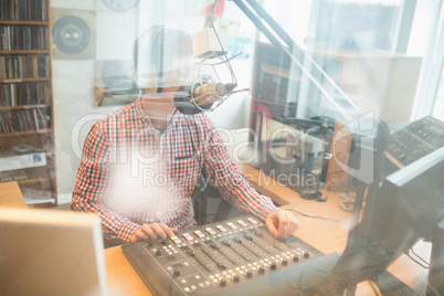 Radio host operating sound mixer in studio