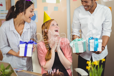 Happy colleagues with gifts looking at businesswoman