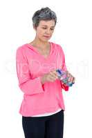 Mature woman opening water bottle while listening music