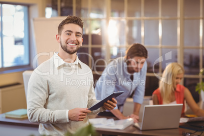 Confident businessman using digital PC with colleagues working