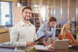 Confident businessman using digital PC with colleagues working