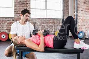 Fit woman lifting dumbbells with trainer