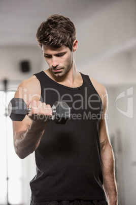 Serious muscular man lifting dumbbell
