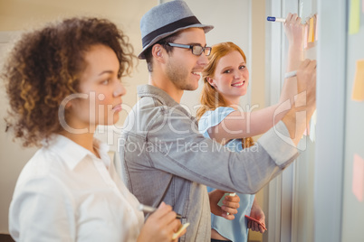 Businesswoman writing on adhesive notes on glass wall with colle