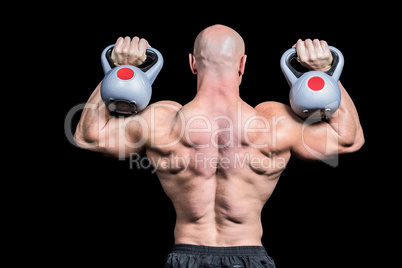 Rear view of bald man lifting kettlebells