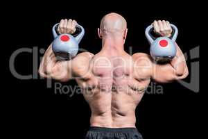 Rear view of bald man lifting kettlebells