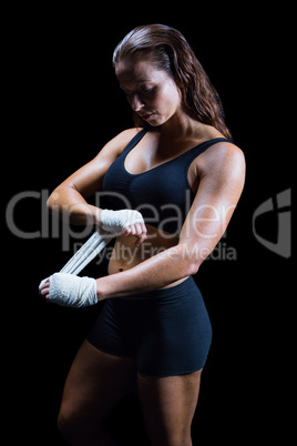 Beautiful athlete tying bandage on hand