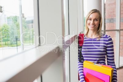 Happy young female student by window