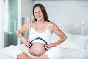 Portrait of pregnant woman with headphones on belly