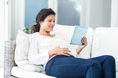 Happy woman reclining on sofa with tablet