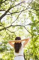 Low angle rear view of woman relaxing against trees