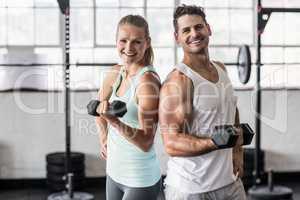 Back to back couple exercising with dumbbells