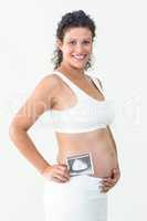 Smiling pregnant woman holding an ultrasound scan