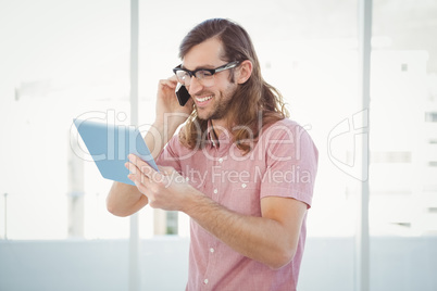 Hipster with mobile phone looking at digital tablet