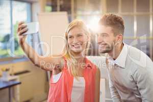 Businesswoman taking selfie with male colleague