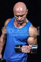 Bald man in blue vest lifting dumbbells