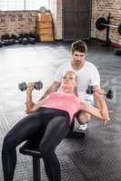 Fit woman lifting dumbbells with trainer