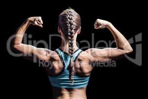 Rear view of woman with braided hair flexing muscles