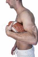 Side view of shirtless rugby player holding ball