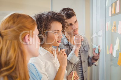 Businesswoman touching adhesive note on glass