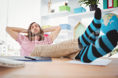 Hipster resting with legs on desk in office