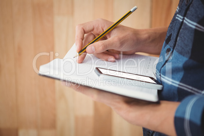 Cropped image of businessman writing with pencil on book