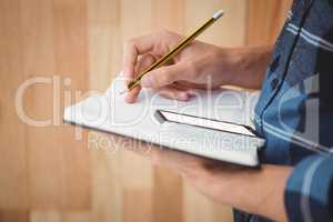 Cropped image of businessman writing with pencil on book