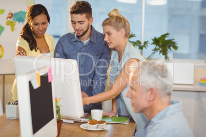 Business people using computer as male colleague working