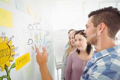 Man pointing at wall with sticky notes and drawings