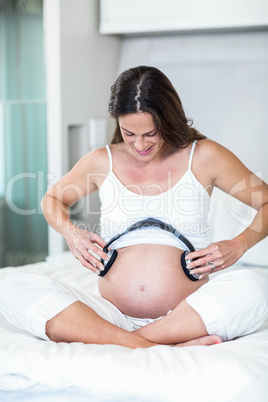 Happy woman with headphones on pregnant belly