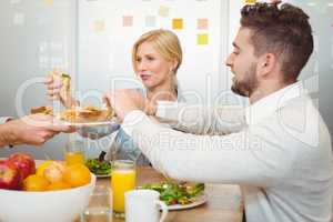 Cropped image of businessman serving sandwiches to colleagues