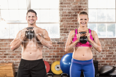 muscular smiling couple with kettlebells