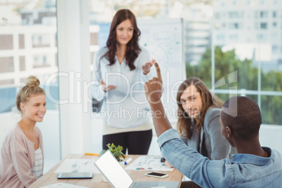 Man with hand raised while discussing with coworkers