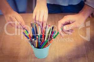 Business people choosing pencils from desk organizer