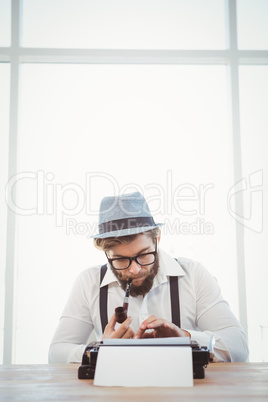 Hipster smoking pipe while working at desk